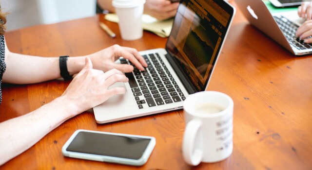 Womanusingmacbooklaptoponbrownwoodentable