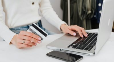 Personholdingbankcardnexttolaptopandphone